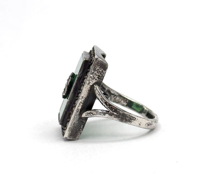Seen edge-on from the opposite side, the tall bezel wall and its beaded border stand proud of the split shank, with the green stone visible as a narrow band along the rectangular face.