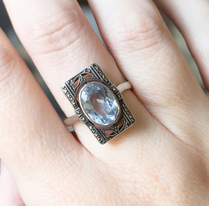 Closer view on the finger, the rectangular face tilted so the milgrain edges, pierced petal-shaped openings and slim shank meeting the frame are visible against darkened silver.