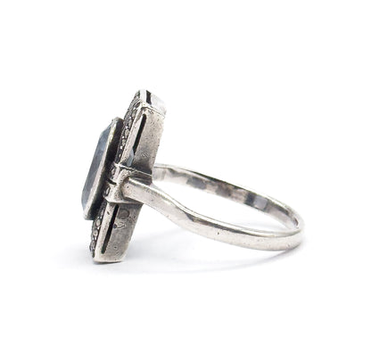 Strict profile against white, the rectangular face seen edge-on so its slim depth and marcasite-set sides show, with the shank sweeping back in a full curve to the right.