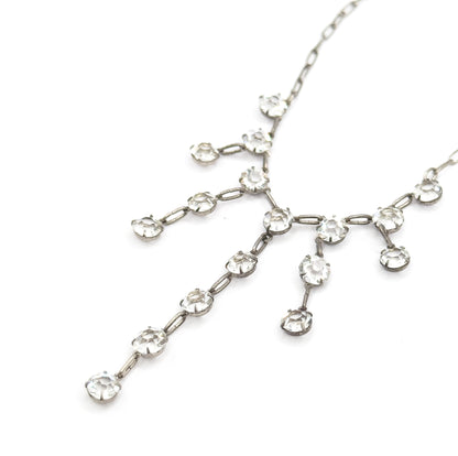 Angled view with the fringe set diagonally across the white background, the chain running off to the upper corners and the longest strand of paste stones trailing toward the lower left.
