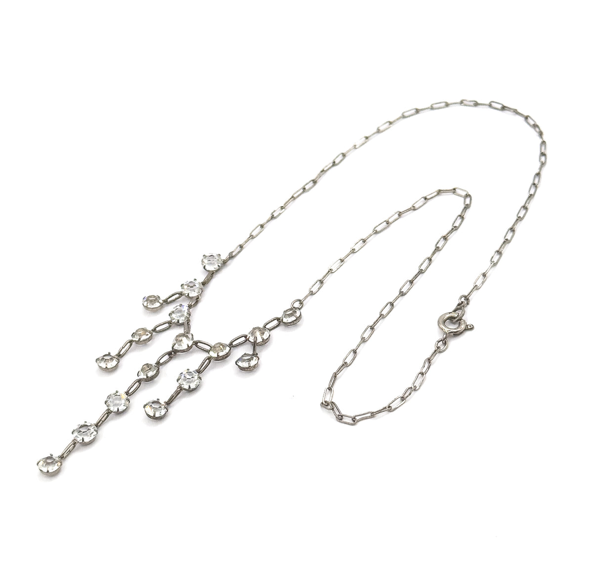 Laid flat on a white background in a full loop, showing the entire length from the round spring ring clasp at one side to the paste fringe drops spread out at the other.