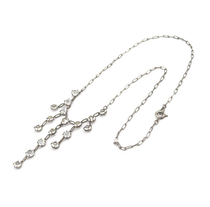 Laid flat on a white background in a full loop, showing the entire length from the round spring ring clasp at one side to the paste fringe drops spread out at the other.