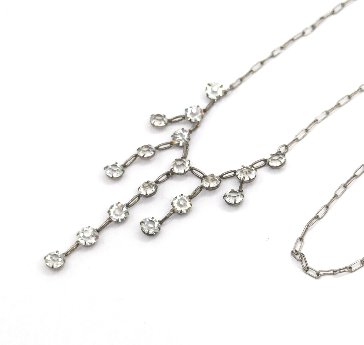 Close view of the fringe section on white, showing each paste stone held in its own small prong setting linked by short oval bars into branching, tapering strands.
