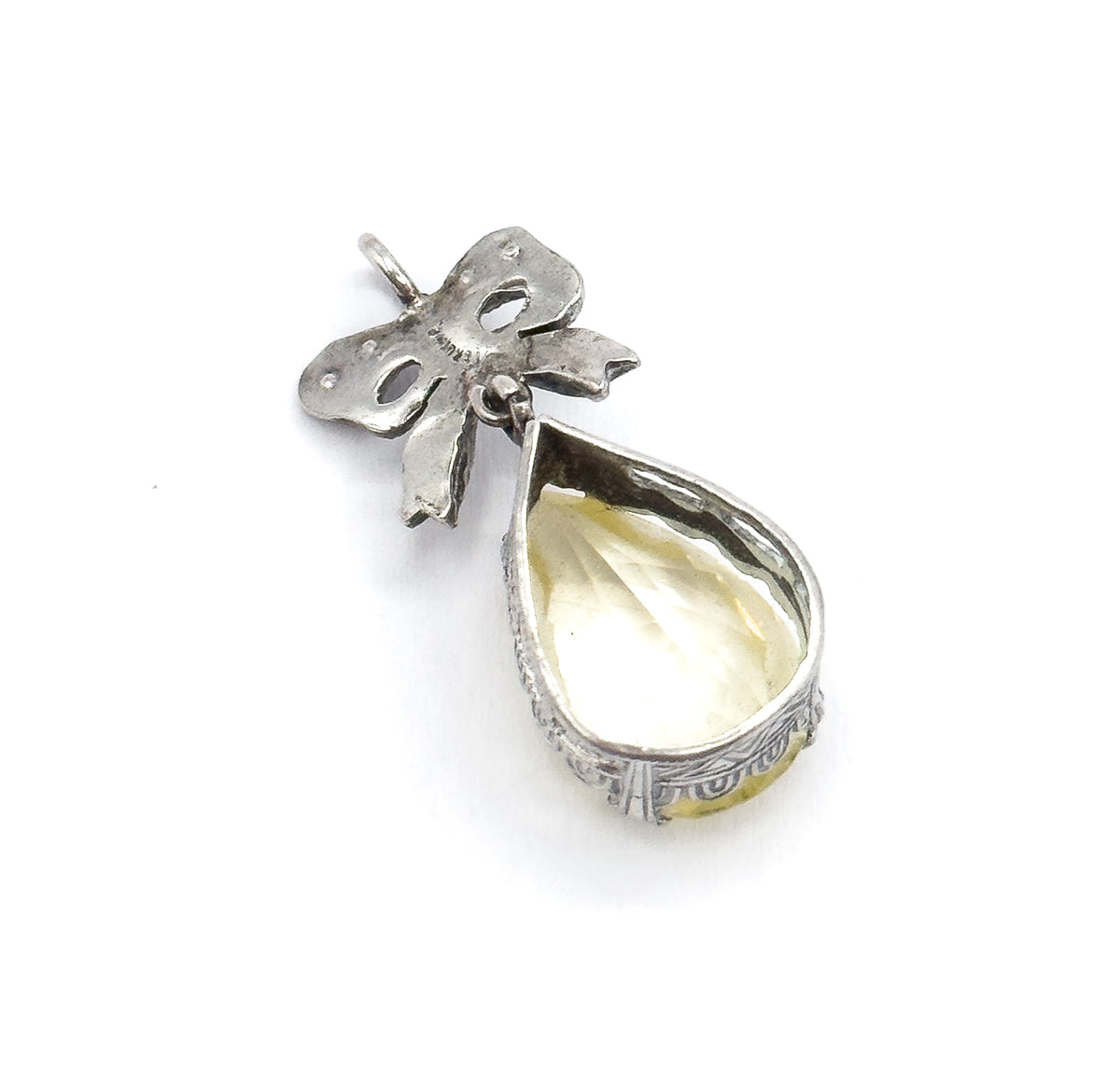 Angled back view against white, showing the open-backed teardrop setting with its patterned gallery, the lime-coloured stone visible through it, and the small bail above the bow.