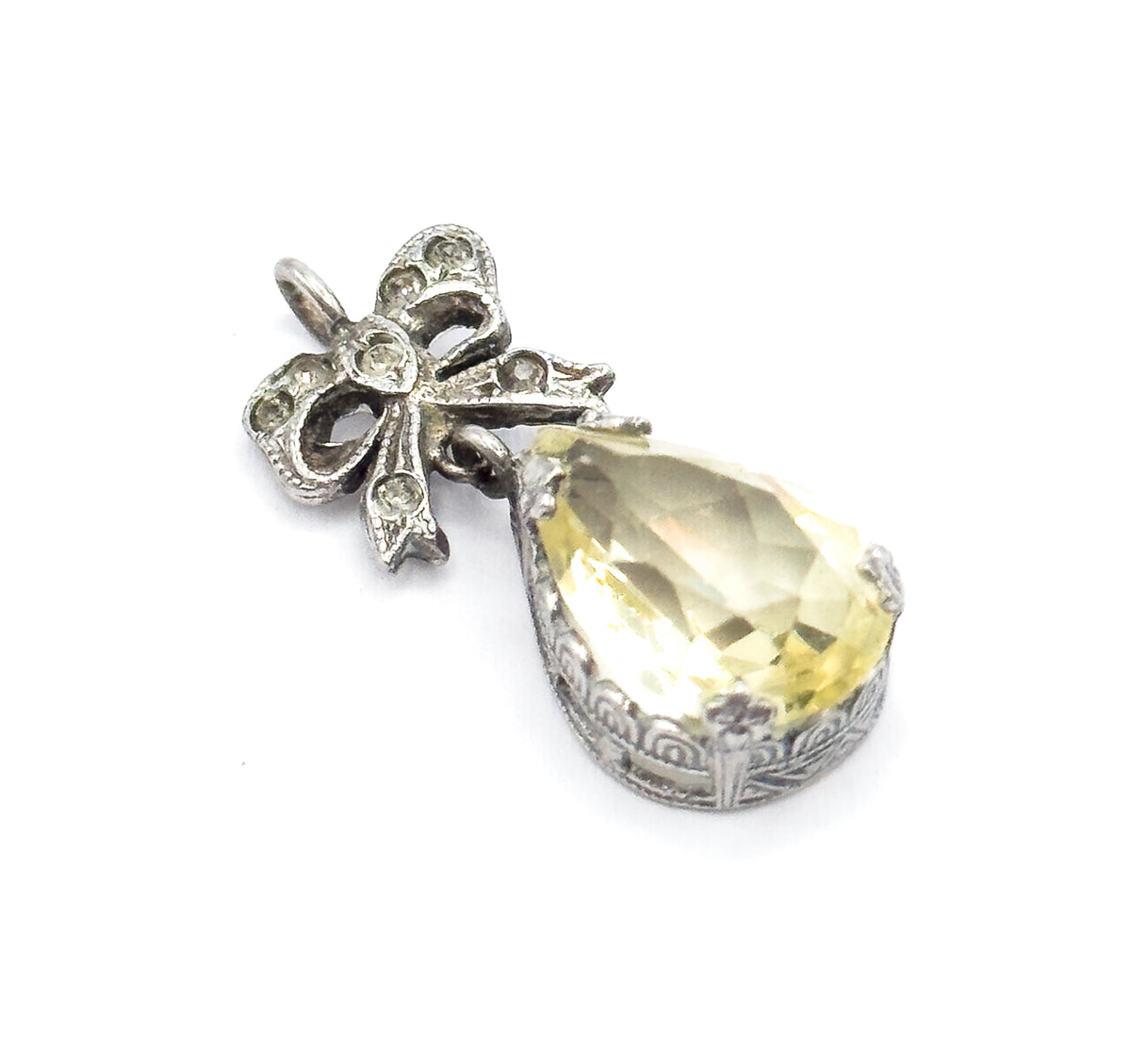 Diagonal view with the bow lying upper left, its small clear stones set in round collets, and the scrolled openwork along the side of the teardrop setting clearly visible.