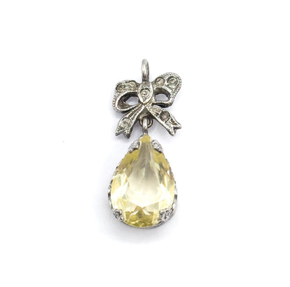Straight-on front view filling the frame, showing the pendant's full symmetry: round bail above a sterling silver bow set with small clear stones, over the lime-coloured teardrop in its prong-set bezel.