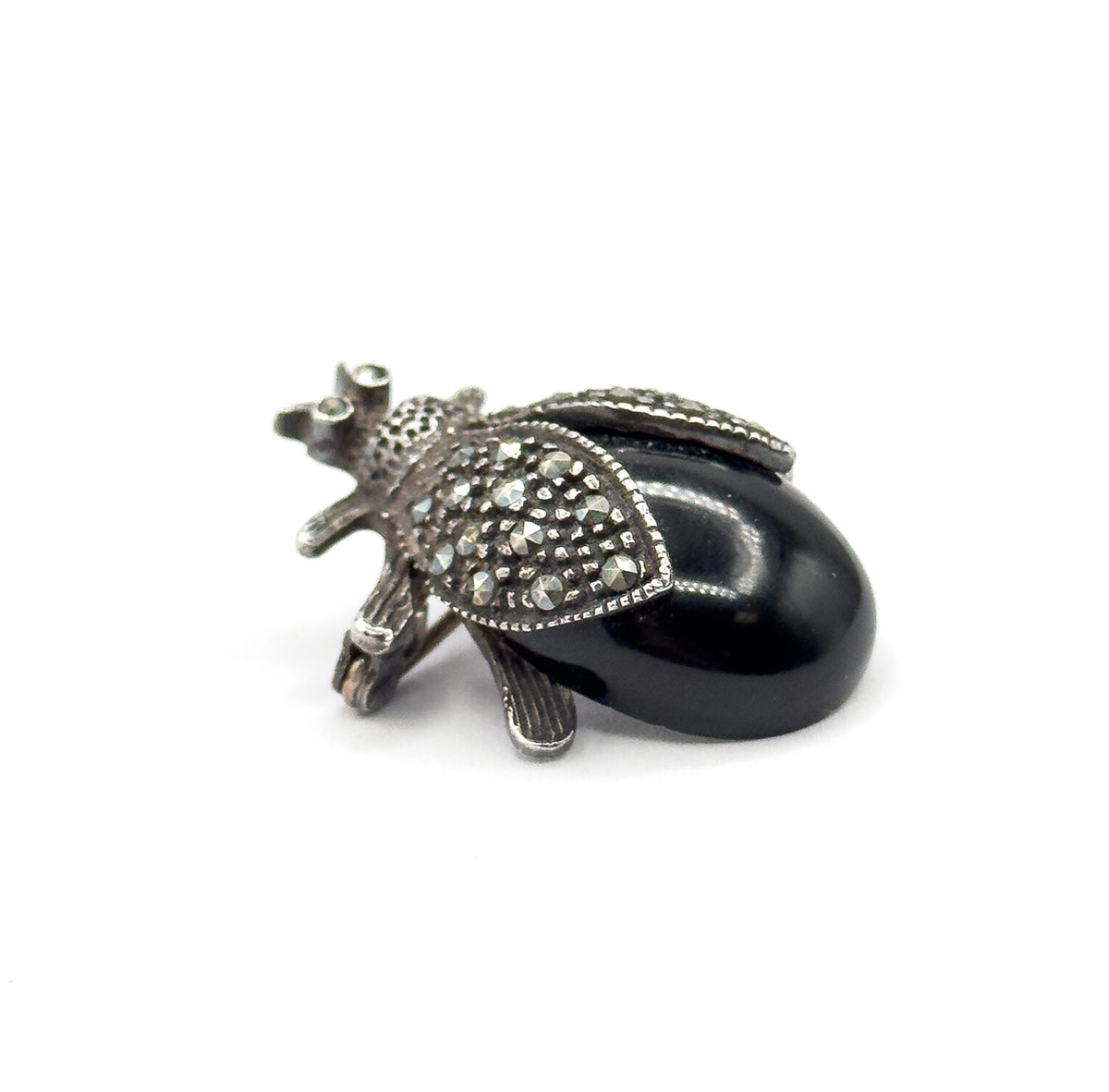 Almost the same view with slightly different angle, closer in from the side so the black cabochon's full dome, both small-stone-set wings and the textured legs stand out against white.