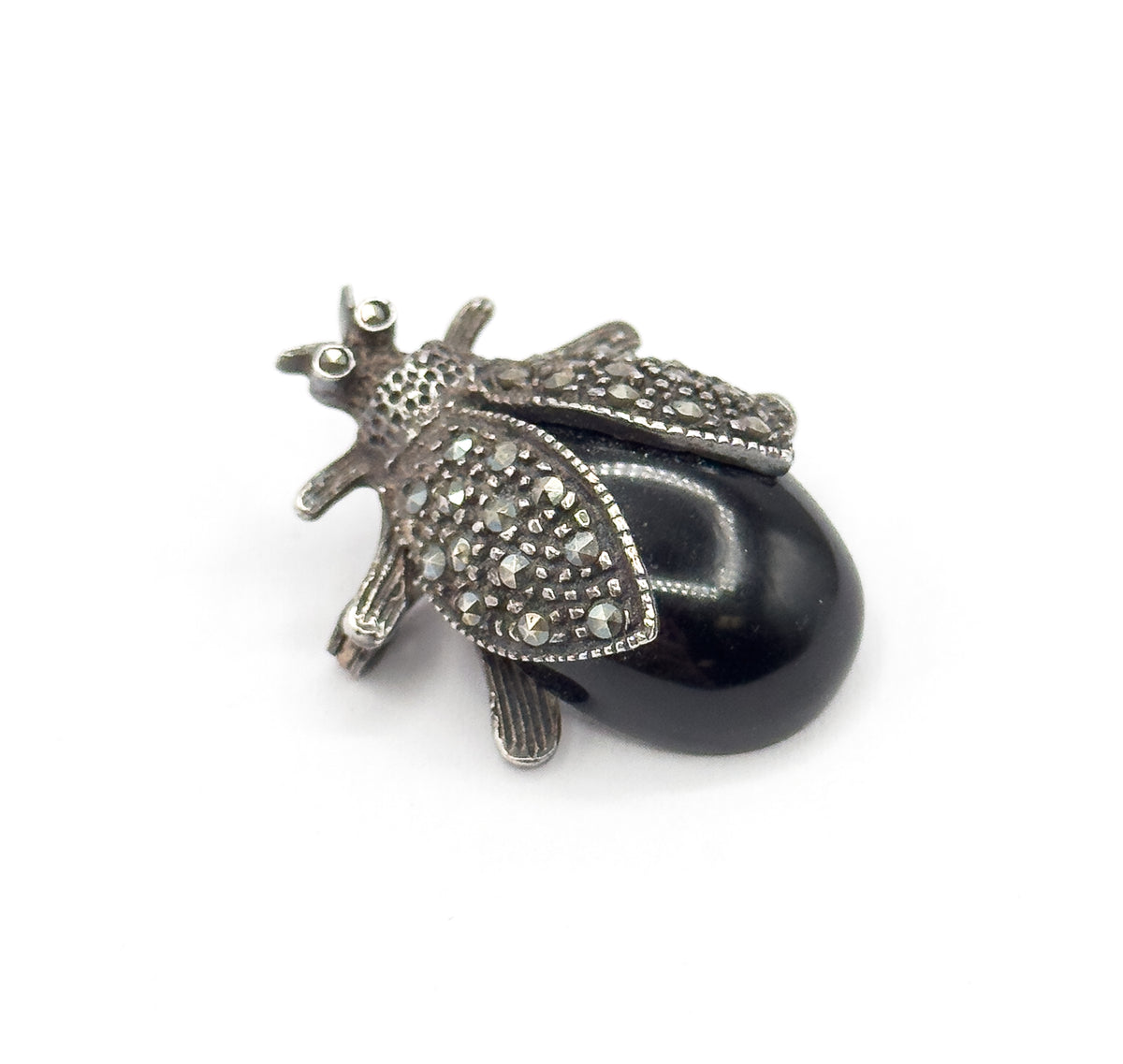 Close top view on white, the head's two tiny round eye stones and slender antennae now clear, with both small-stone-set wings swept back over the smooth black cabochon body.