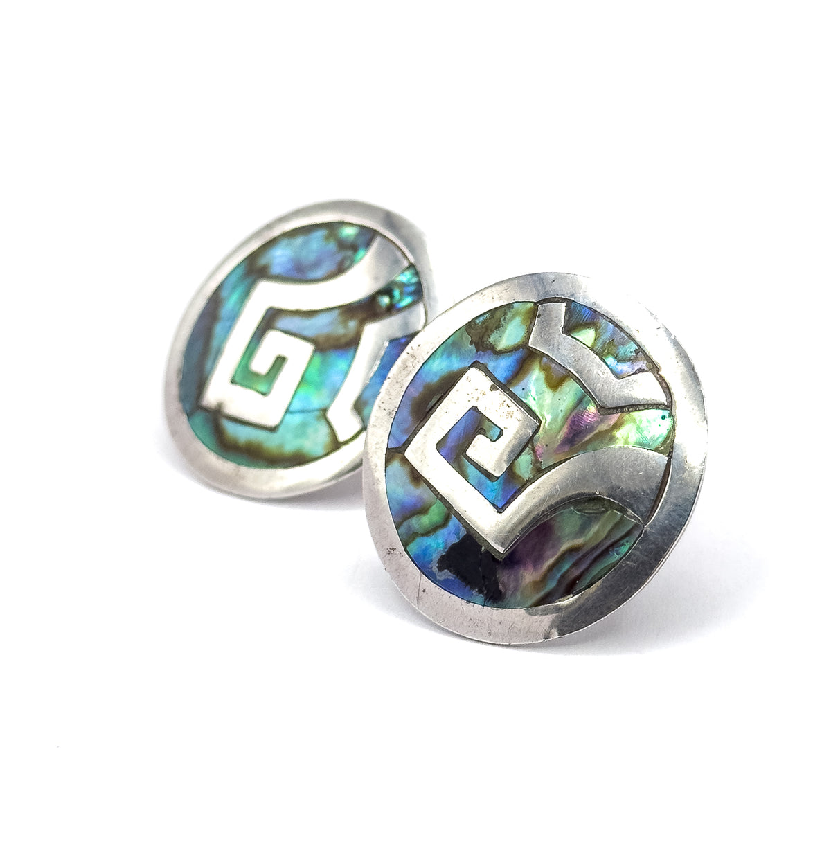 Tight three-quarter view with one disc tipped forward in sharp focus, its stepped silver spiral and abalone catching blue, green and violet while the second disc sits softly behind.