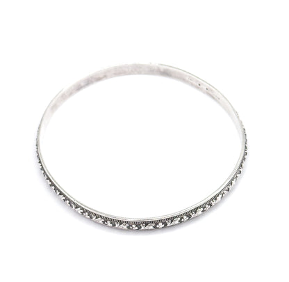The full circle of the bangle seen from above against a white background, with the carved flower-and-leaf band and beaded borders running along the lower rim and a stamp visible inside the upper curve.