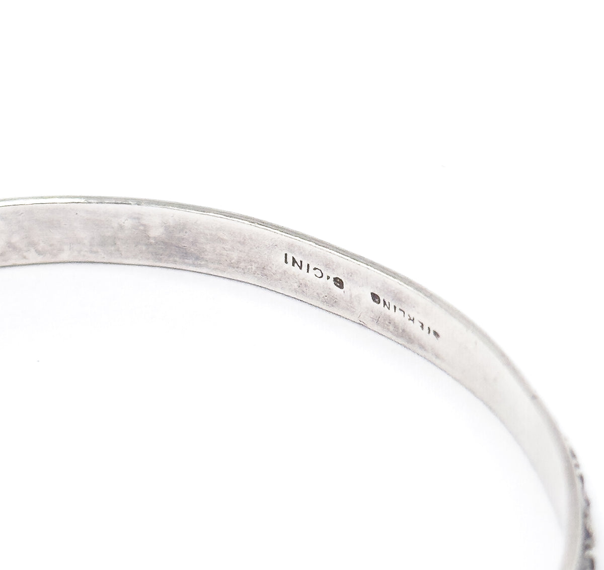 Close-up of the inside of the band, where the maker's stamp reading CINI and the word STERLING are struck into the smooth inner surface, with the beaded edge just visible at right.