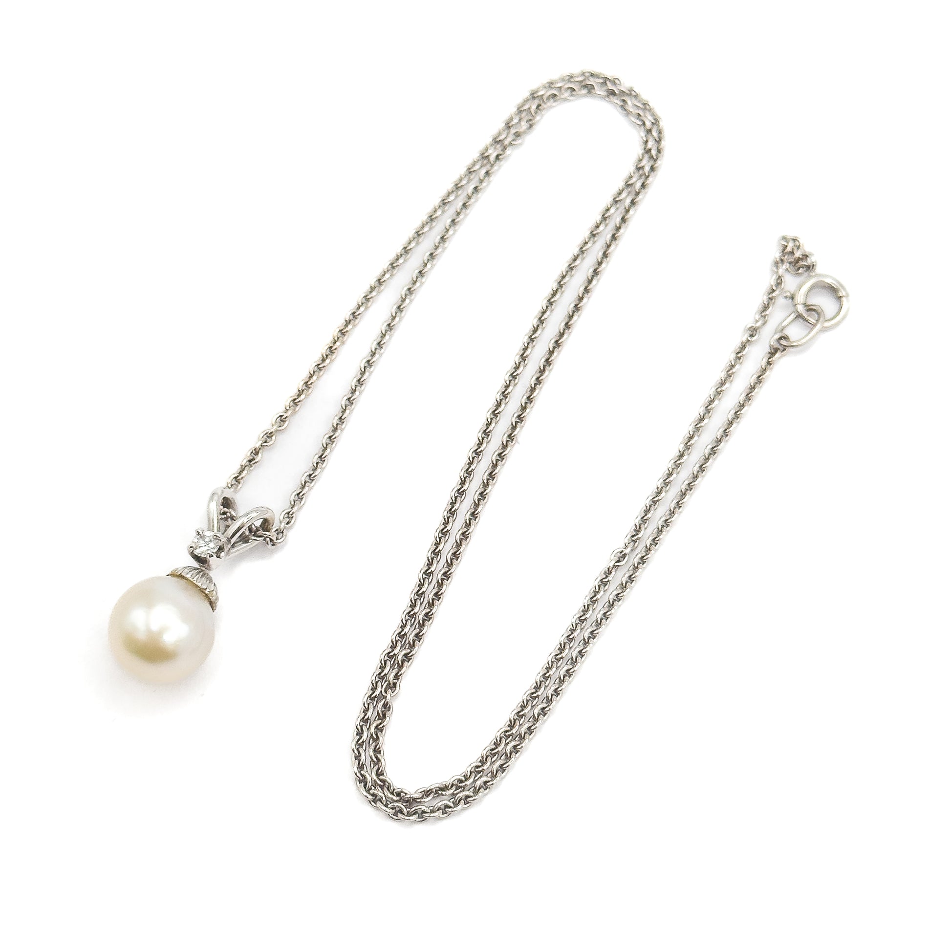 The whole necklace laid out flat, the doubled chain looping down the frame to the spring-ring clasp at upper right, with the pearl pendant and its diamond-set bail at lower left.
