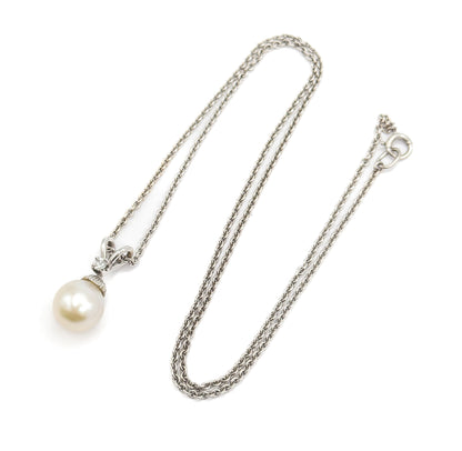 The whole necklace laid out flat, the doubled chain looping down the frame to the spring-ring clasp at upper right, with the pearl pendant and its diamond-set bail at lower left.
