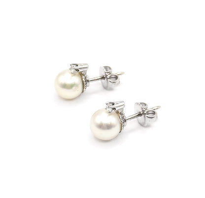 The pair sits at a three-quarter angle with both white gold posts running back to their butterfly backs, showing how little the pearls and diamonds stand off the earlobe.