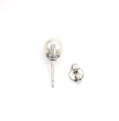 A mid-century pearl and diamond earring in 14K white gold, shown on its side against white with the long post and buttercup gallery visible, its separate post back lying alongside.