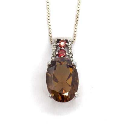 Straight-on frontal view with the box chain rising in a wide V to both top corners, the amber-brown oval quartz centred below its vertical bar of two red stones and tiny clear ones.