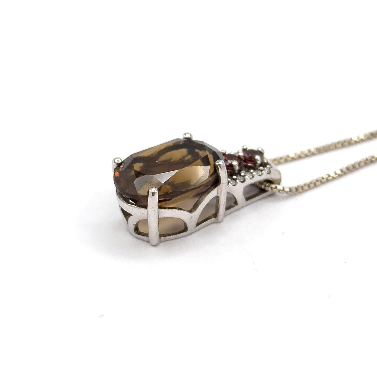 Low side-on view where the pendant's arched openwork gallery and the long prongs gripping the quartz stand out in profile, the box chain running off to the upper right corner.