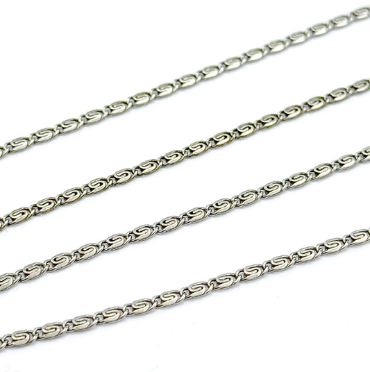 The chain doubled back on itself in four parallel diagonal rows across white, filling the frame so each interlocking S-link reads clearly.
