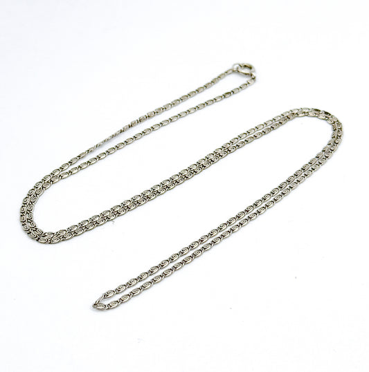 The whole sterling silver necklace laid flat in one long narrow loop on white, the spring-ring clasp at the top end and the S-links running unbroken down both sides.