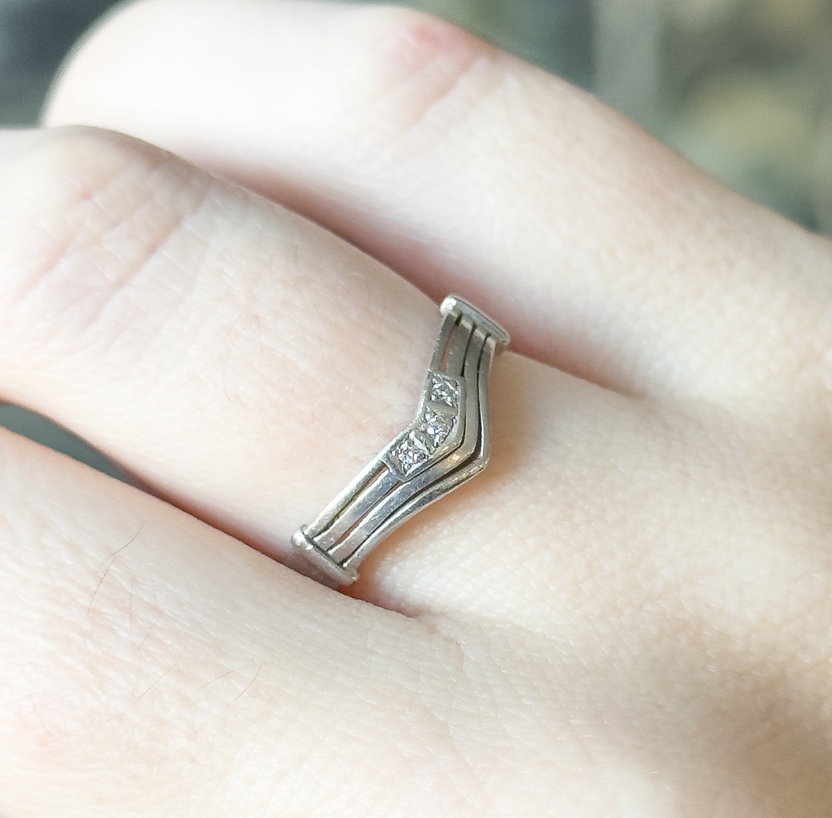 Overhead close view across the knuckle, showing the low profile of the chevron band and the grooved lines running the length of the shank to the flat end caps.
