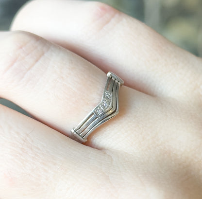 Overhead close view across the knuckle, showing the low profile of the chevron band and the grooved lines running the length of the shank to the flat end caps.