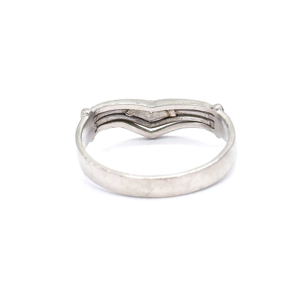 Rear view of the platinum band lying flat, so the back of the chevron shows its grooved lines and end prongs above the broad smooth sweep of the shank below.
