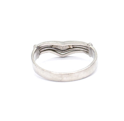 Rear view of the platinum band lying flat, so the back of the chevron shows its grooved lines and end prongs above the broad smooth sweep of the shank below.