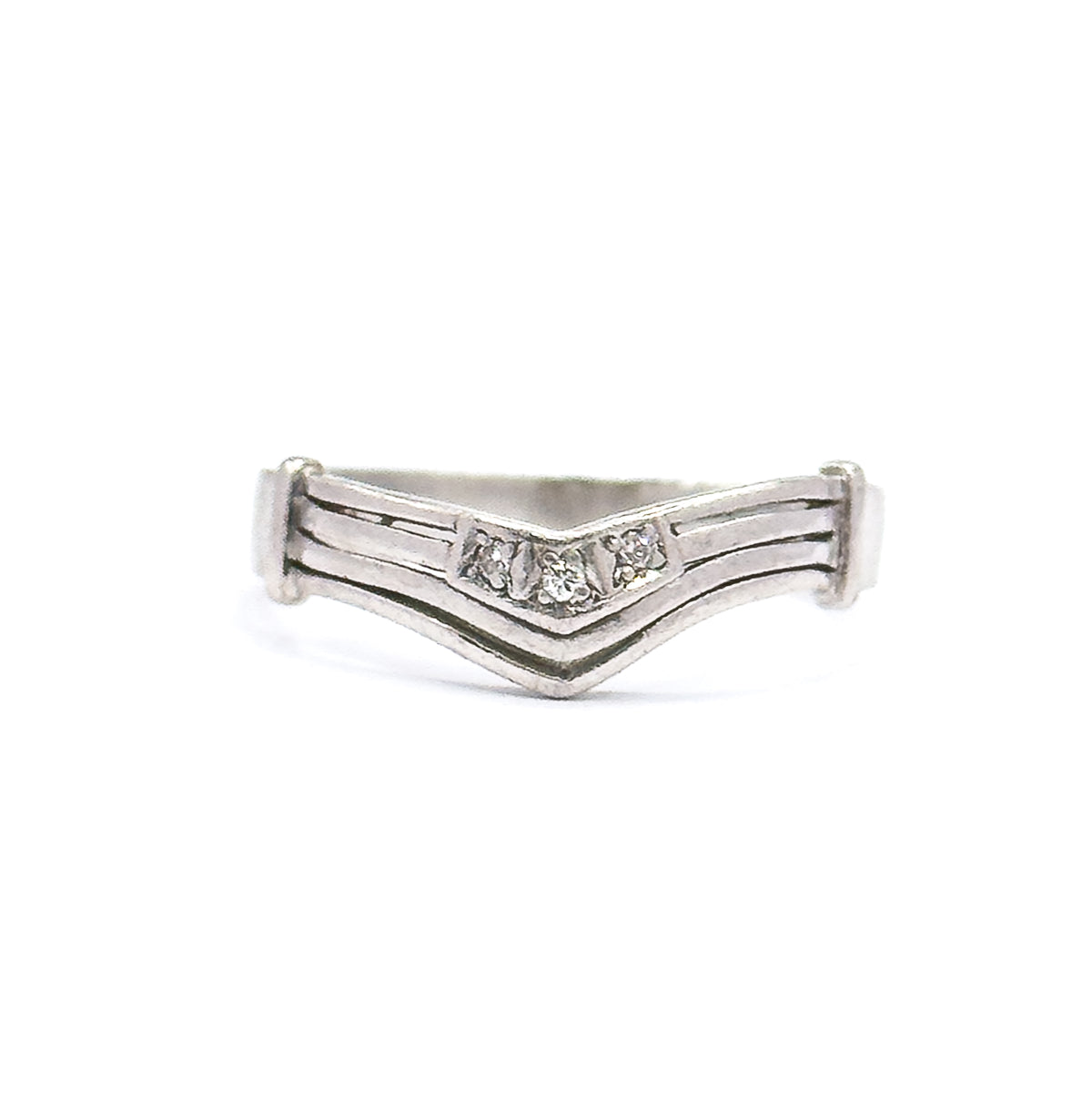 Straight-on front view of the platinum band standing upright, the chevron dipping to a point at centre with its three small diamonds in a row and grooved lines running out to flat end caps.