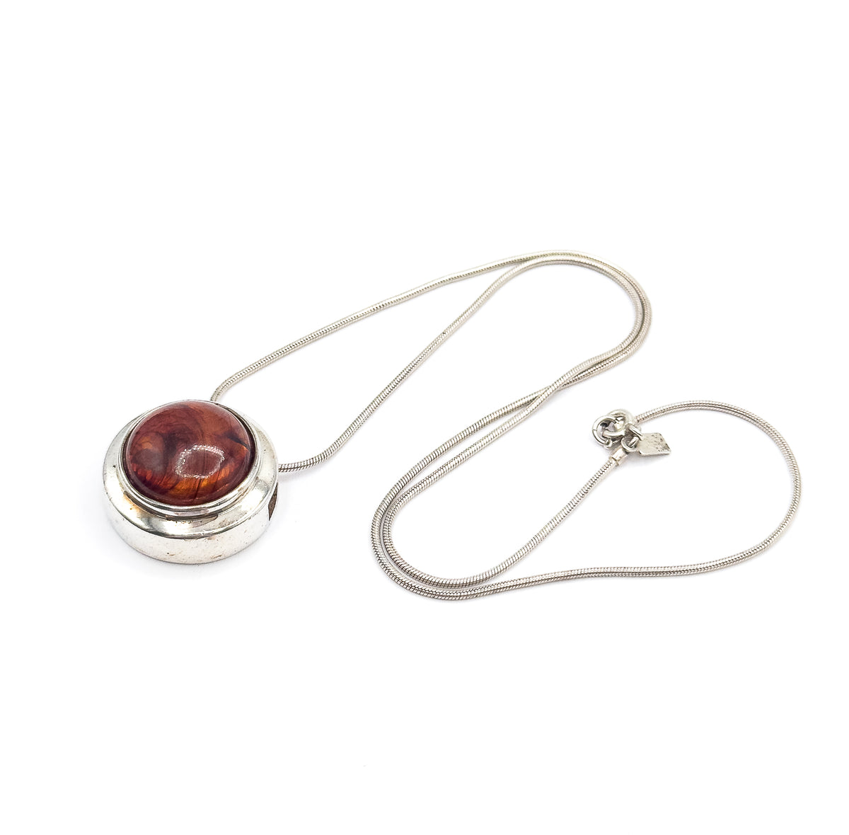 The whole necklace laid out, the slide pendant at the left and the snake chain looping round to the clasp ring and small flat stamped tag on the right.