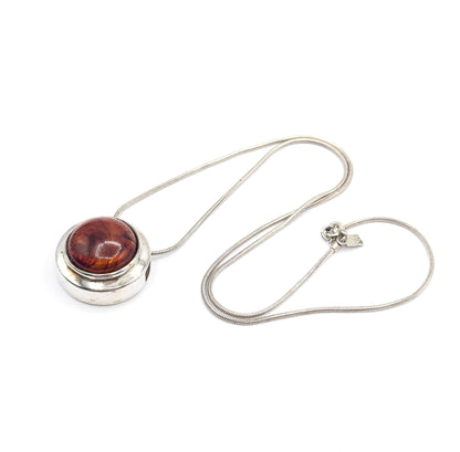 The whole necklace laid out, the slide pendant at the left and the snake chain looping round to the clasp ring and small flat stamped tag on the right.
