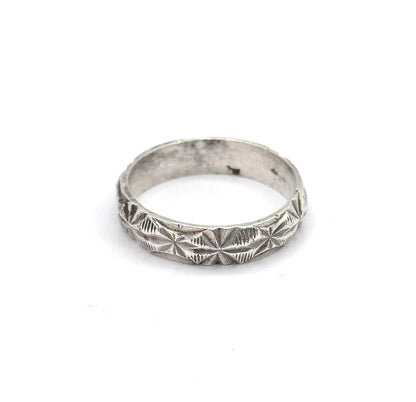 Tilted low on the white background so the eye looks down into the open circle of the shank, the darker patina inside contrasting with the bright faceted outer surface.