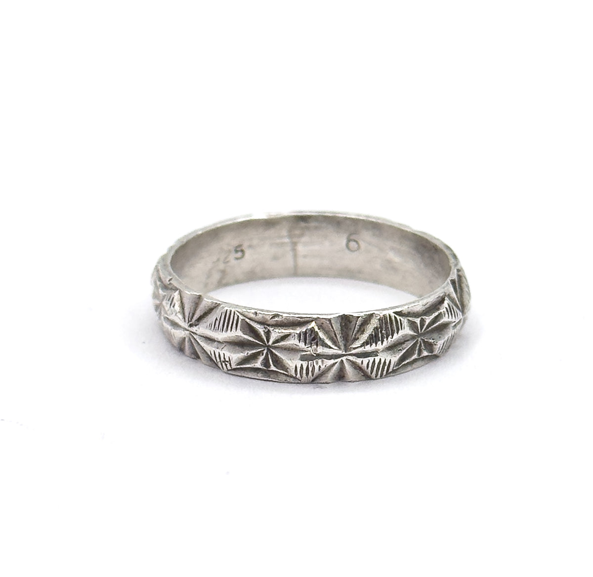 Straight-on and close, the sterling silver band fills the frame so the diamond-cut starbursts and coin-edge rims read clearly, with faint stamped numerals visible on the inner back wall.