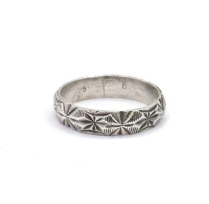 Straight-on and close, the sterling silver band fills the frame so the diamond-cut starbursts and coin-edge rims read clearly, with faint stamped numerals visible on the inner back wall.