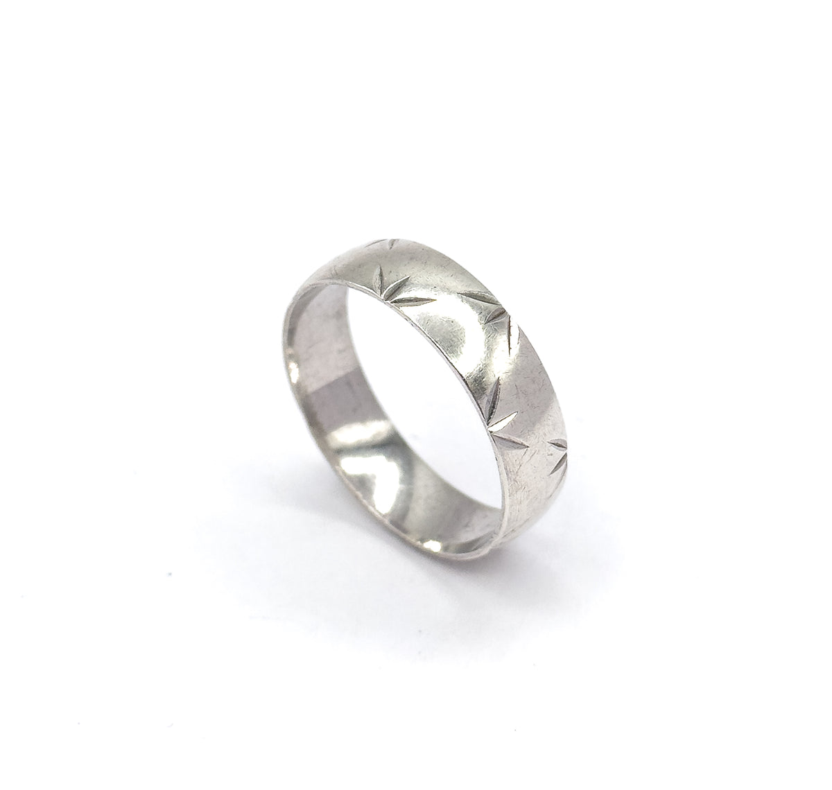 Tipped further back on the white background, the band's open circle faces the viewer so the star-cut pattern runs away around the far side of the shank.