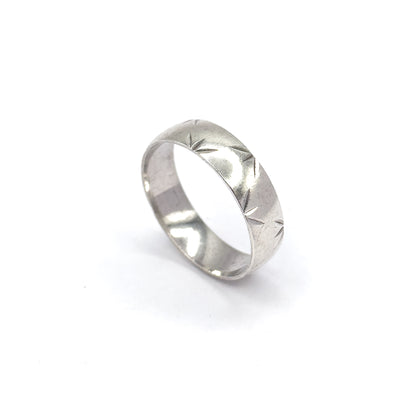Tipped further back on the white background, the band's open circle faces the viewer so the star-cut pattern runs away around the far side of the shank.