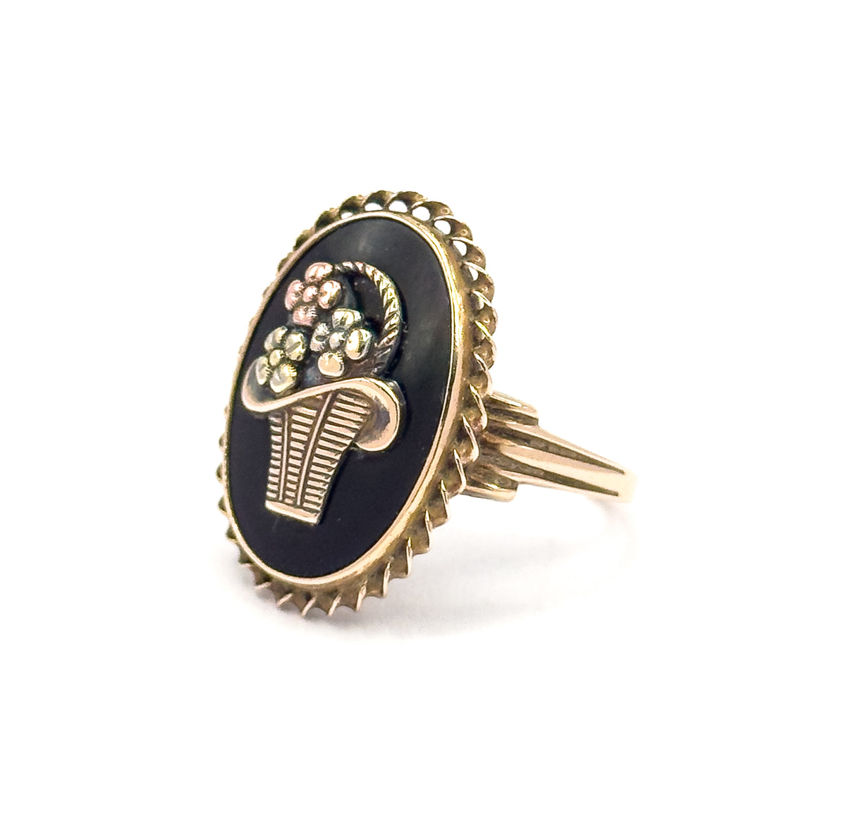 Tilted side-on view showing the depth of the oval bezel and its scalloped rope edge, with the split, grooved shoulders flaring out from the shank up to the back of the setting.