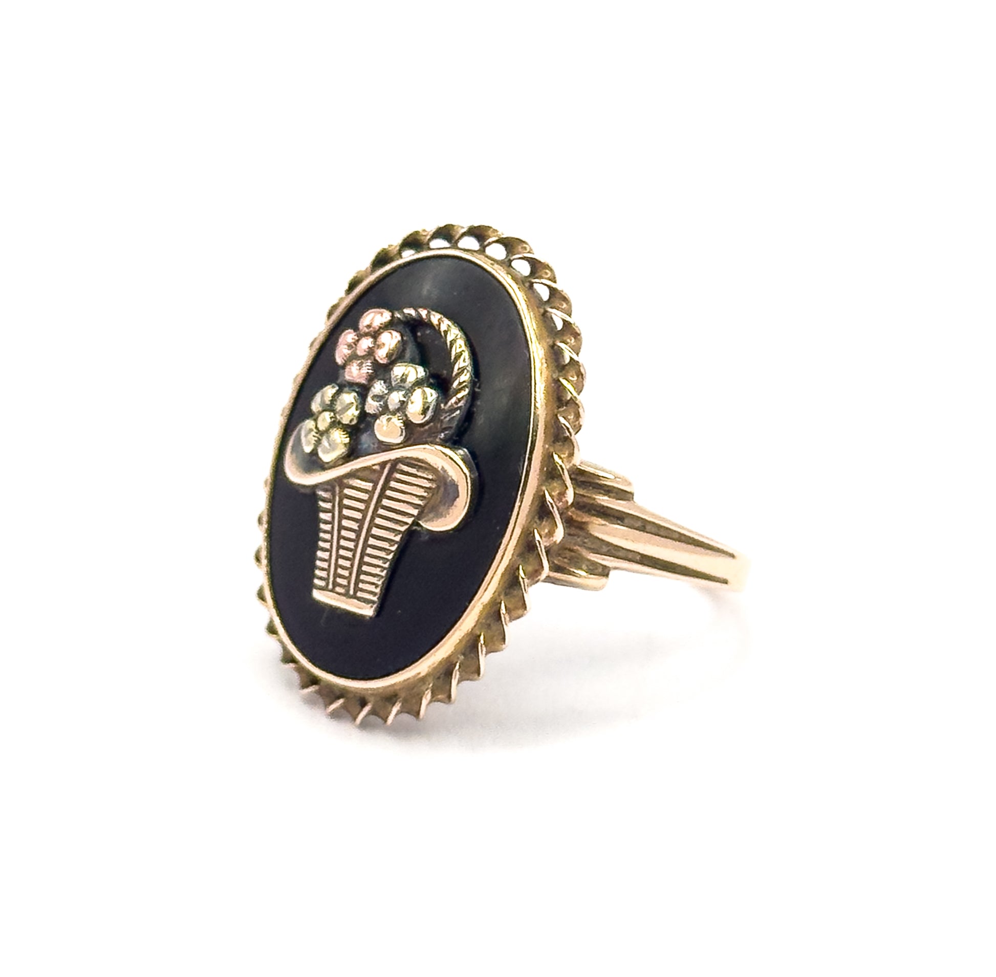 Tilted side-on view showing the depth of the oval bezel and its scalloped rope edge, with the split, grooved shoulders flaring out from the shank up to the back of the setting.