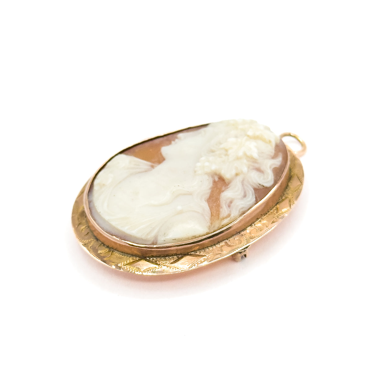 Tilted view from a lower angle with the cameo face turned toward the viewer, the small catch just visible peeking past the engraved frame's lower right edge beneath the bail.