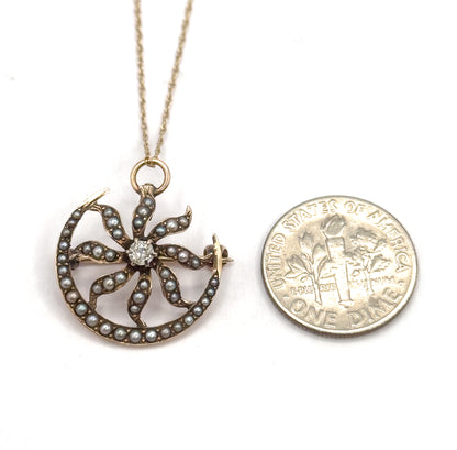 Laid flat on white beside a dime for scale, the pendant only slightly wider than the coin, its chain rising from the ring bail to the top of the frame and the pin stem showing at the right.