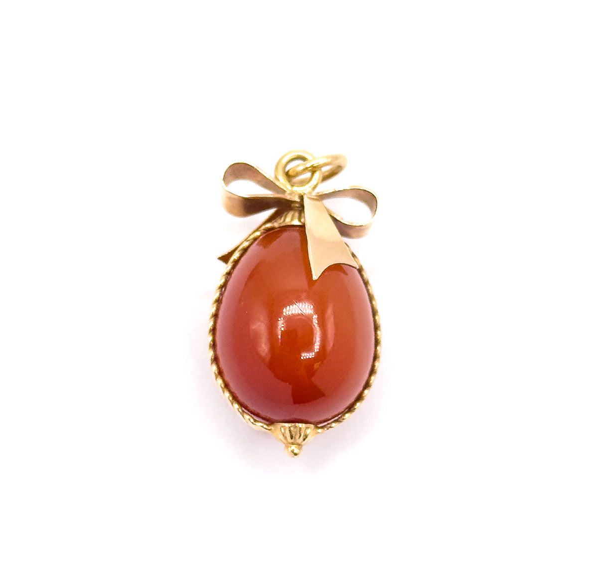 Mid-century carnelian egg charm in 14K yellow gold, shown front-on against a plain white background, the polished egg framed by twisted cable wire with a ribbon bow and jump ring above.