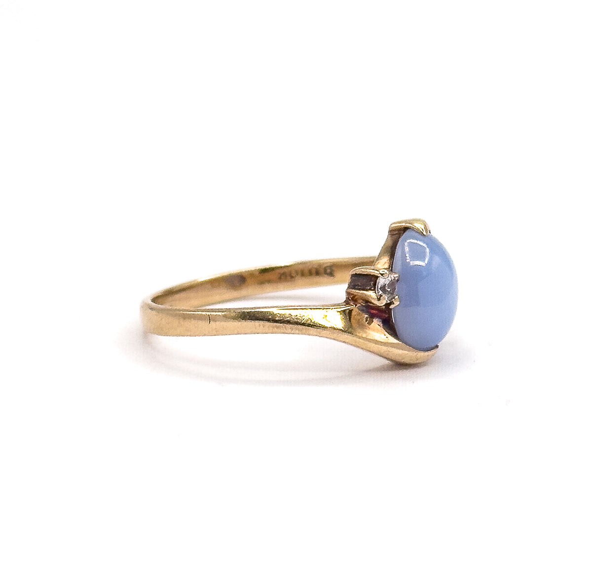 Almost the same view with slightly different angle, lower and closer so the prong tips and the open gallery under the periwinkle cabochon show, with faint stamping inside the shank.