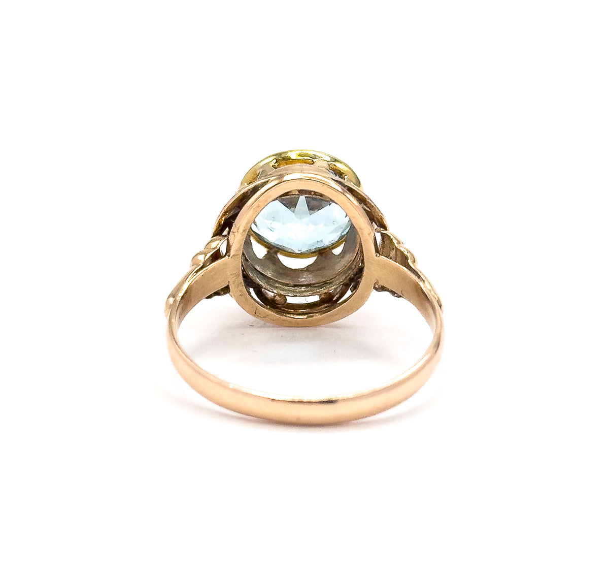 Seen from the back with the shank looping toward the viewer, the open underside of the bezel shows the topaz from beneath, framed by the rose gold knotwork gallery.