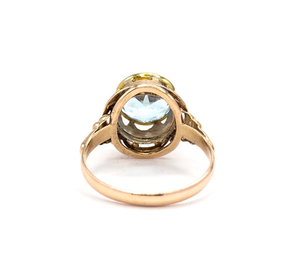 Seen from the back with the shank looping toward the viewer, the open underside of the bezel shows the topaz from beneath, framed by the rose gold knotwork gallery.
