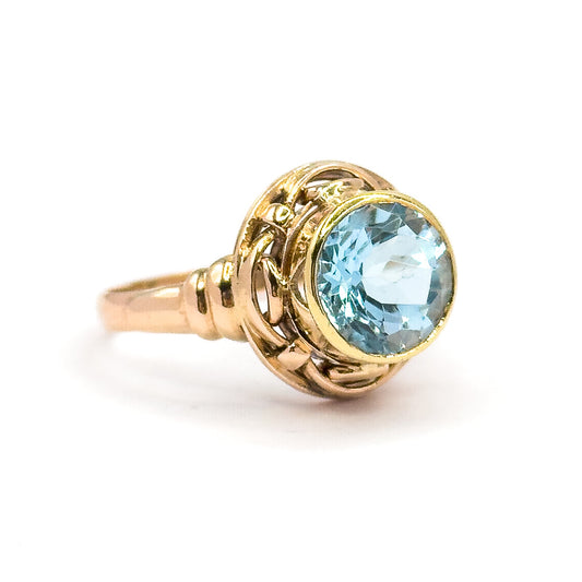 Off the hand now against a plain white background, seen from the side so the yellow gold bezel, the interlaced rose gold knotwork gallery and the slim tapering shank stand clear.