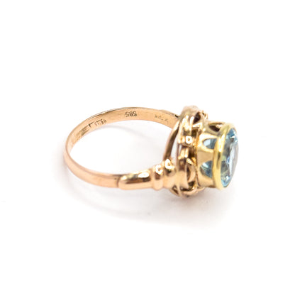 Viewed from behind and below, the inside of the slim rose gold shank turns to the camera showing small stamped marks, with the yellow gold bezel and knotwork gallery angled away.