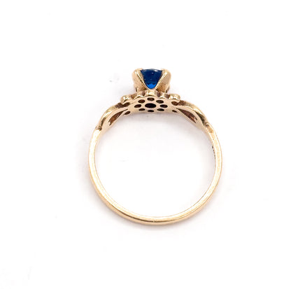 Seen from behind, the open back of the setting shows the pierced gallery holes beneath the cobalt spinel and the full circle of the yellow gold shank.