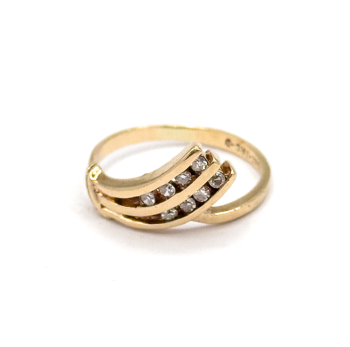 Angled three-quarter view from the front, the curved bars fanning across the finger opening with the eight small round diamonds channel-set in rows, the slim shank crossing behind.