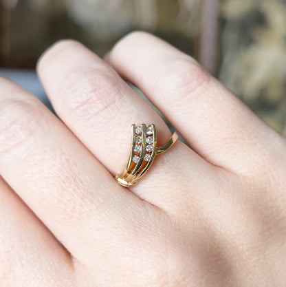 A diamond V-shaped ring in 10K yellow gold, shown on a finger, its two angled rows of small round diamonds fanning across the face above a slim tapering shank.