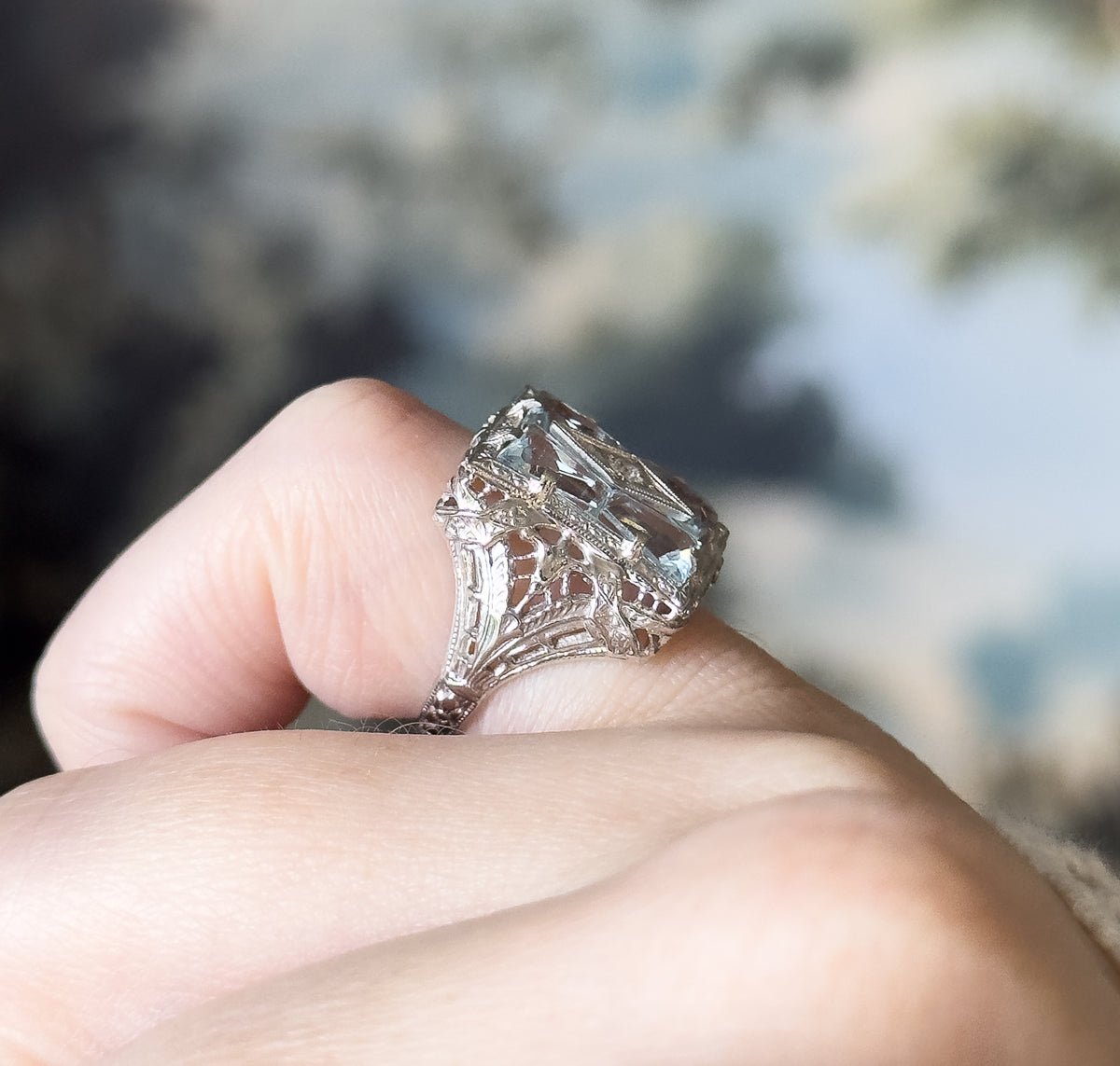 A close side profile shown on a finger, revealing the pierced filigree gallery and how the tall top tapers down to the slim shank.
