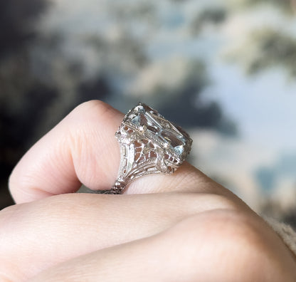 A close side profile shown on a finger, revealing the pierced filigree gallery and how the tall top tapers down to the slim shank.